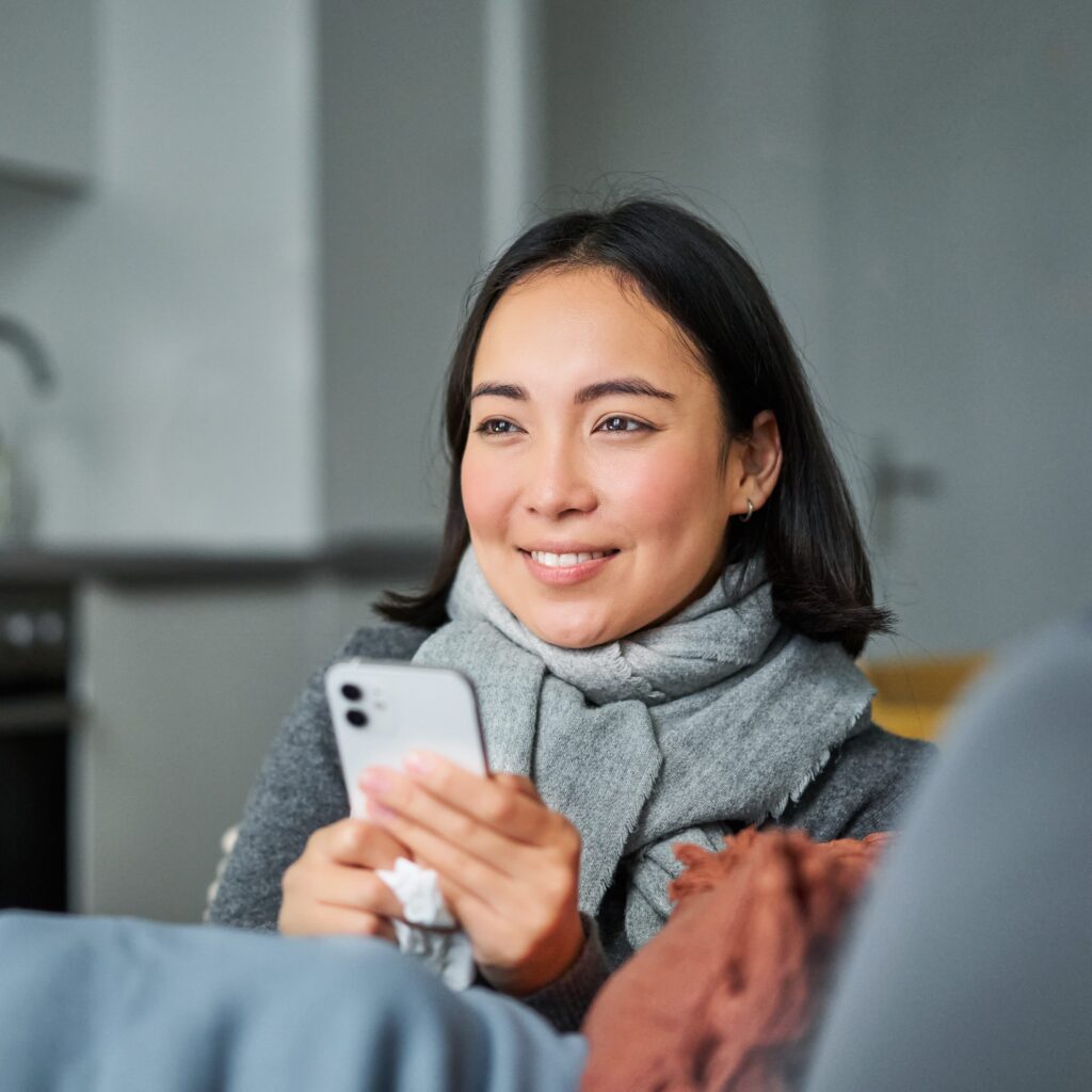 portrait-ill-young-korean-woman-sitting-sofa-texting-message-using-mobile-phone-contact-her-2-edited-1